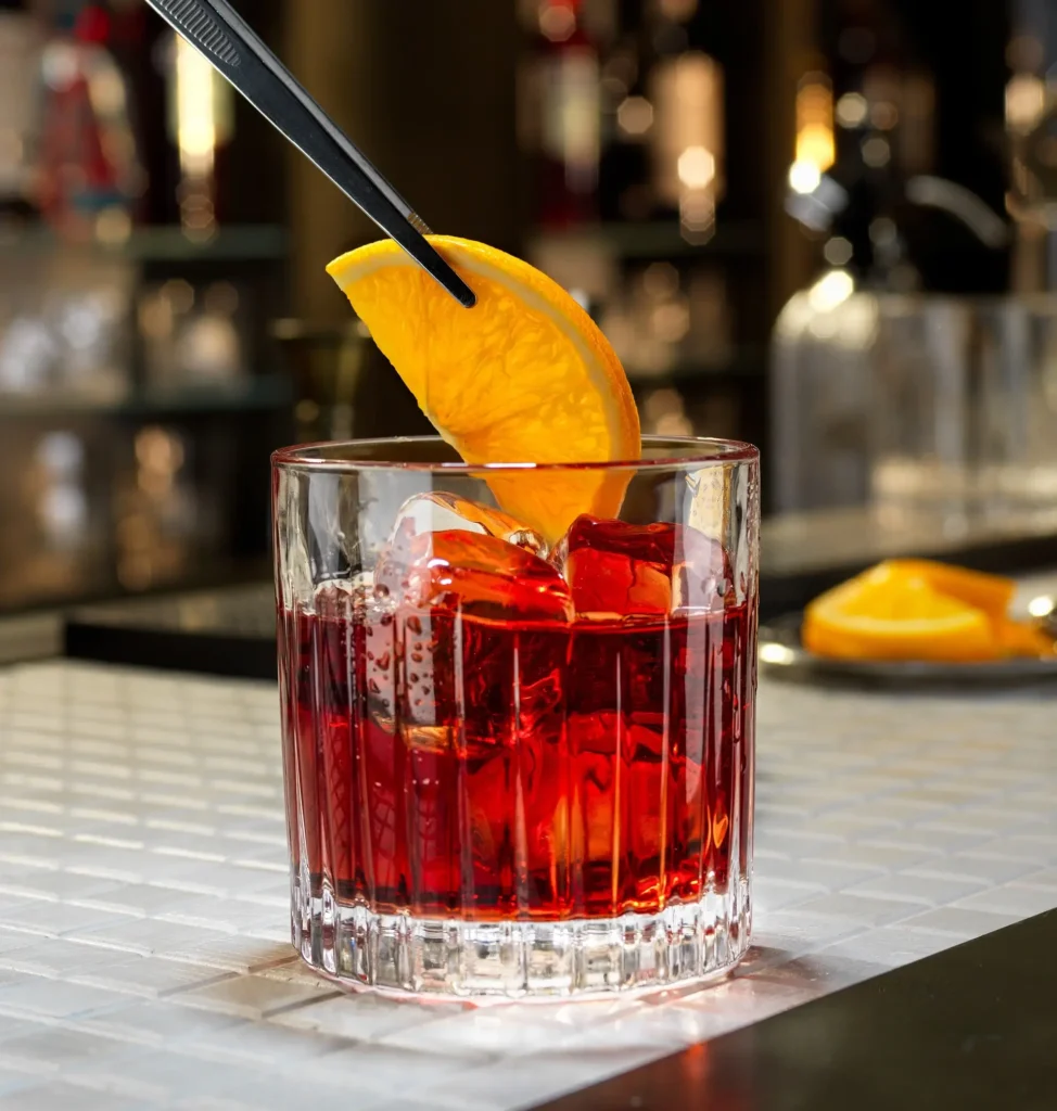 Cốc rượu Gin: Negroni đặt trên bàn, đang được trưng đặt một lát chanh vào